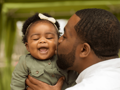 Father holding smiling baby girl during a paternity DNA test in Houston.